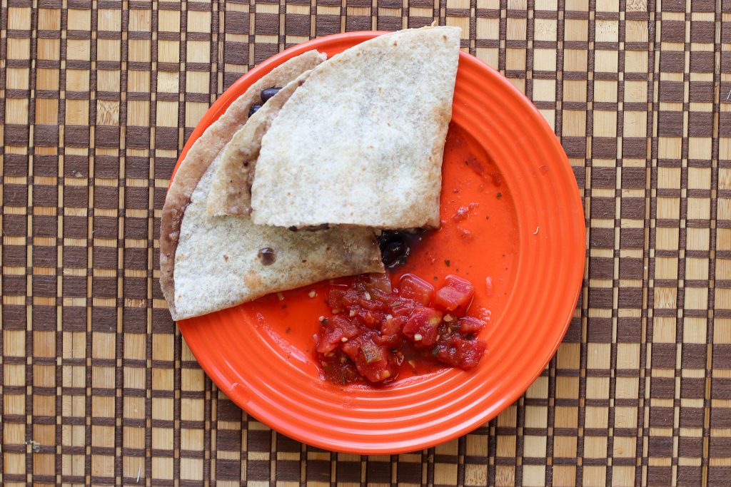 Quesadilla on a blue plate next to an orange