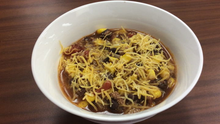 taco soup topped with cheese in white bowl