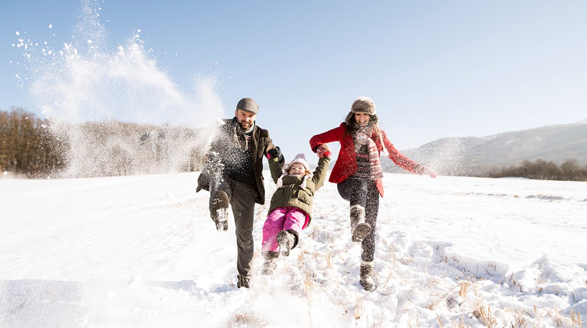father and mother having fun with their daughter, playing in the snow. Sunny white winter nature.
