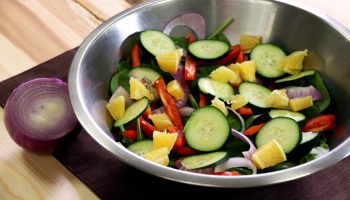 metal bowl with spinach salad and other vegetables