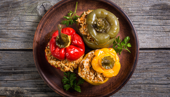 overhead view of cooked stuffed bell peppers on plate on wooden table