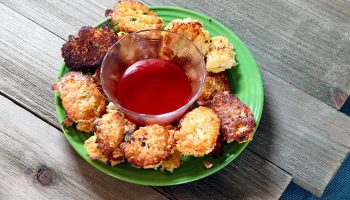 Cauliflower tots on a green plate with red dip